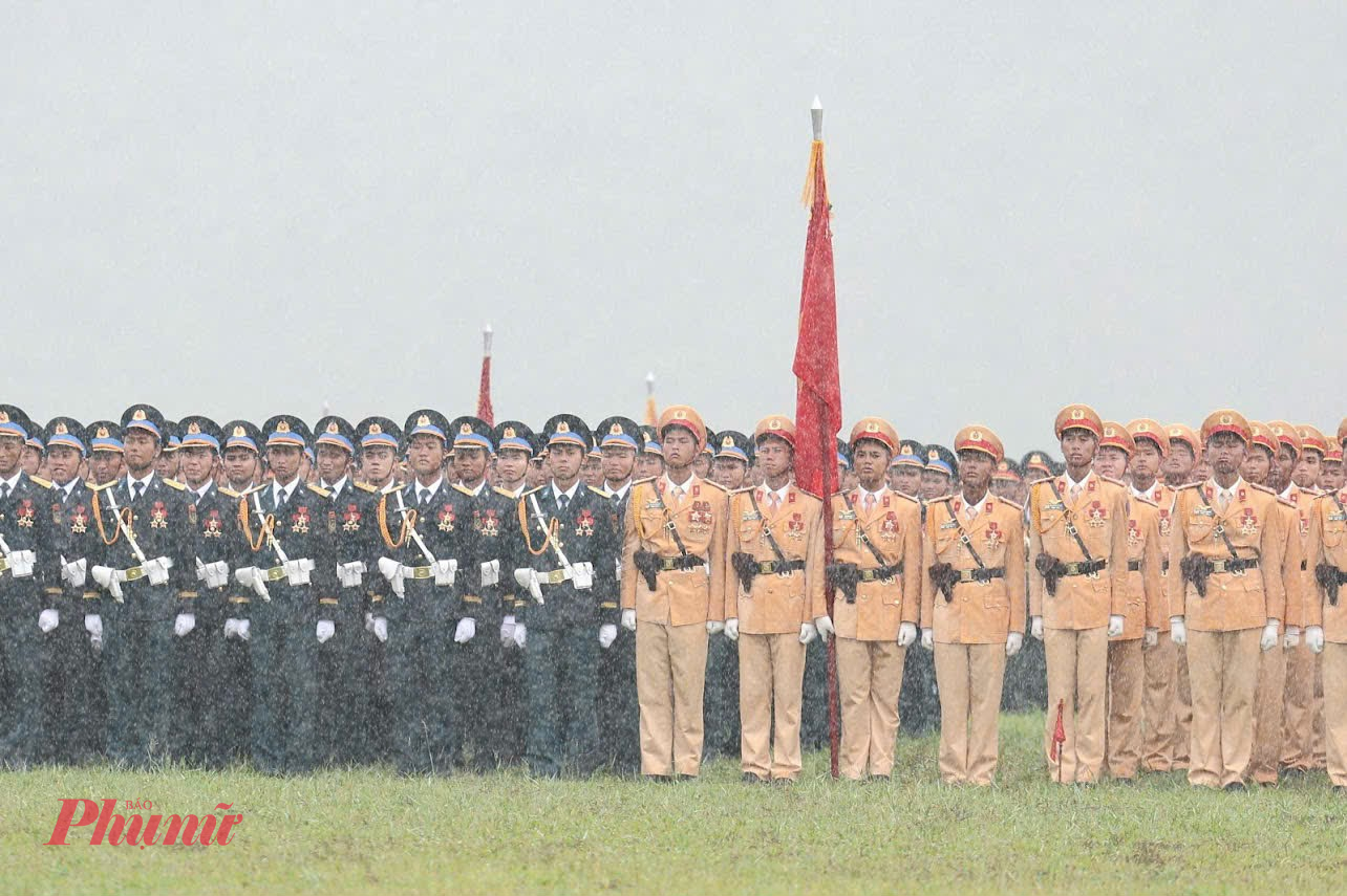 Các khối thực hiện diễu binh, diễu hành đứng nghiêm đứng dưới mưa lớn.