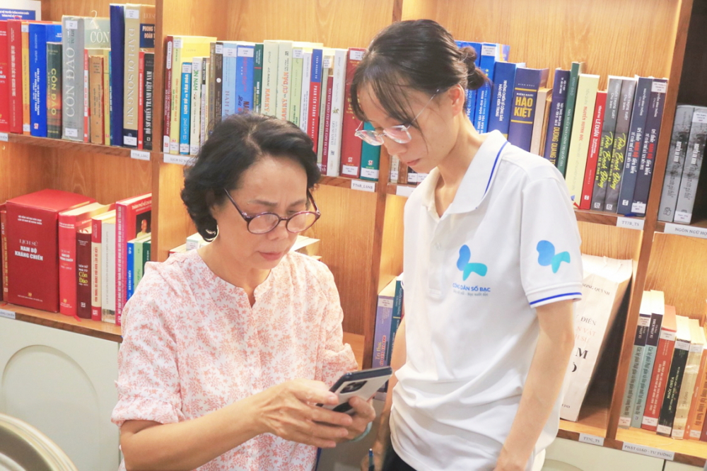 Thành viên dự án hướng dẫn bà Hương thao tác trên điện thoại - ẢNH: CÁT QUÂN