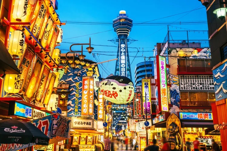 Osaka là thành phố lớn thứ 3 của xứ mặt trời mọc, đứng sau Tokyo và Yokohama. Ở đây có nền ẩm thực phong phú, từ bình dân đến cao cấp nên được mệnh danh là nhà bếp của Nhật Bản”.  Đặc sản ở đây có takoyaki (viên bánh bạch tuộc nướng), okonomiyaki (bánh xèo kiểu Nhật), kitsune udon (mì udon)… Trong ảnh: Khu Shinsekai của Osaka về đêm - Ảnh: Nikada/Getty Images