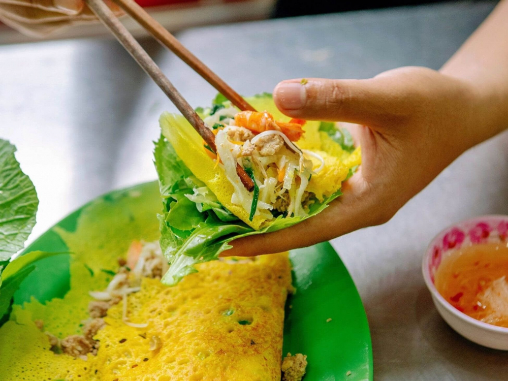 Một địa chỉ ăn đêm nữa mà các tín đồ ẩm thực không thể bỏ qua tại Nha Trang chính là quán bánh xèo mực 70 năm tuổi trên đường Trần Kim Hùng, bánh xèo mực tại đây là món ăn được nhiều người dân địa phương giới thiệu cho du khách trong nước lẫn nước ngoài. Bánh làm từ bột bột gạo, đổ trên khuôn phết sẵn dầu, đường kính hơn nửa gang tay. Phần nhân bánh là mực cơm (hay còn gọi mực trứng) nguyên con, giá, hành. Bạn có thể ăn kèm rau sống và chấm nước mắm ớt để cảm nhận được hương vị đậm đà nhất - Ảnh: MIA