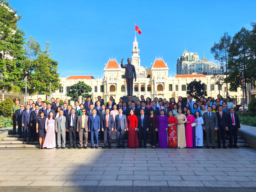 Đoàn đại biểu cùng chụp ảnh lưu niệm trước tượng đài Chủ tịch Hồ Chí Minh và UBND TPHCM
