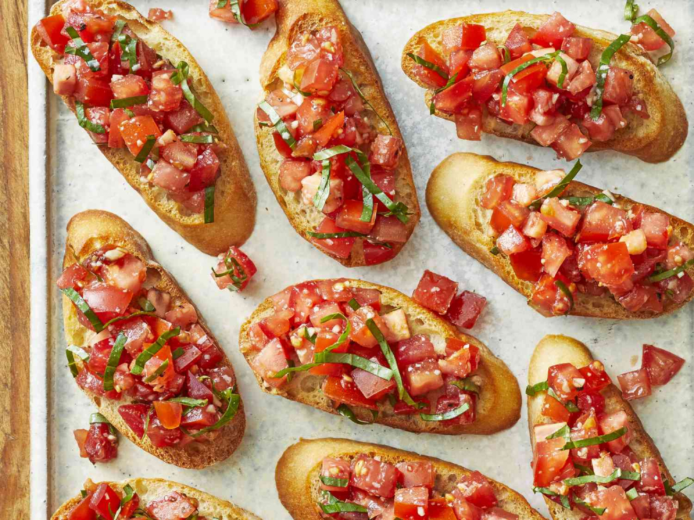 Bruschetta là món khai vị Ý nổi tiếng, dễ làm và ngon miệng. Chuẩn bị bánh mì baguette, cắt lát rồi nướng giòn trên chảo hoặc lò nướng. Trộn cà chua bi thái hạt lựu với dầu ô liu, lá húng quế, muối và tiêu. Khi bánh mì nóng, chà nhẹ một tép tỏi lên mặt bánh để tạo hương thơm. Rưới hỗn hợp cà chua lên trên và thêm chút phô mai parmesan bào. Vậy là bạn đã có món khai vị giòn rụm, thanh mát.
