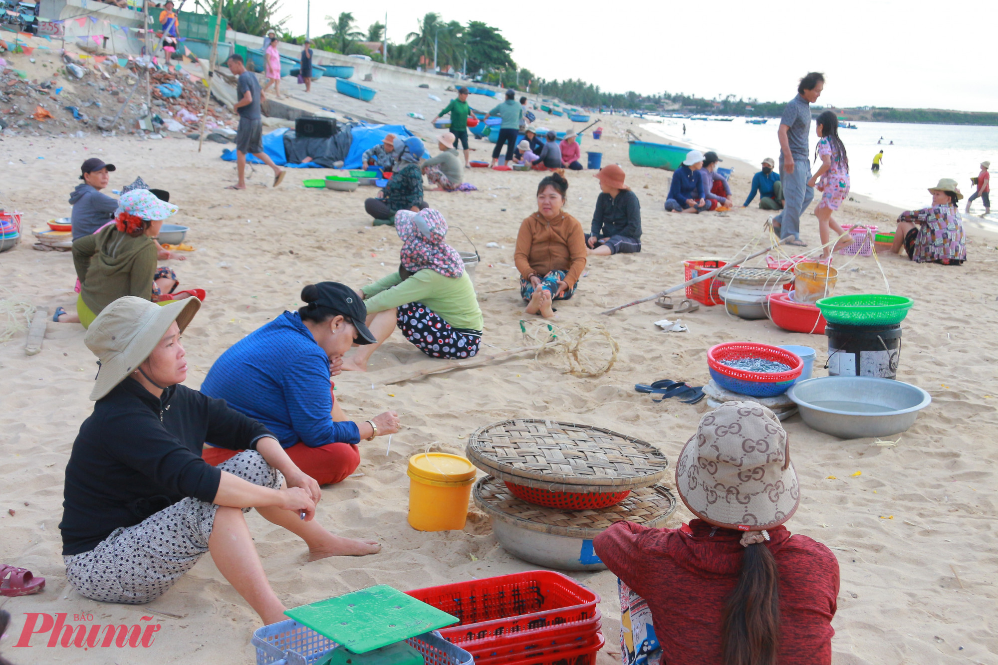 Những người phụ nữ ngồi chờ tàu, thuyền cập bến để mưu sinh