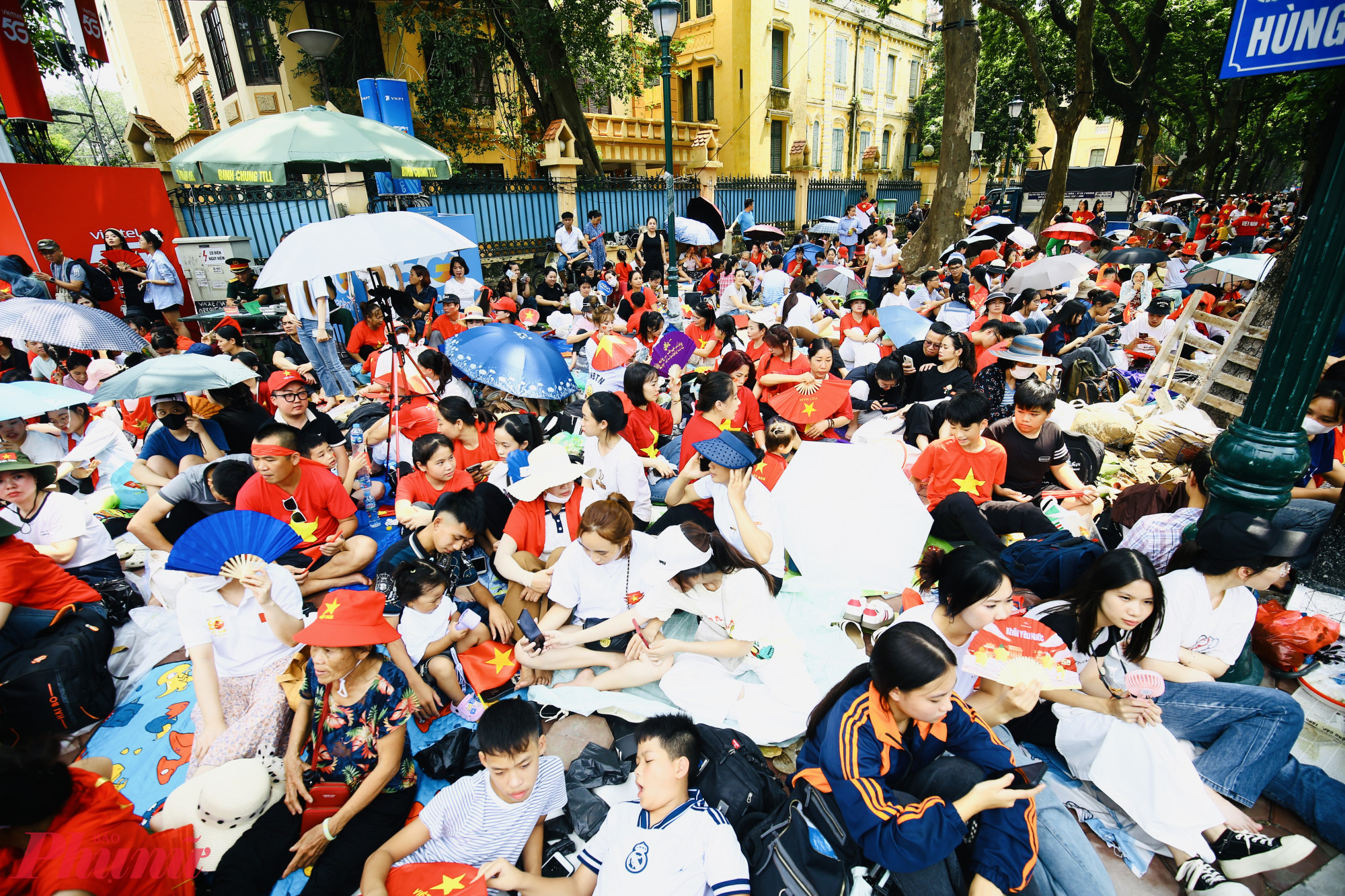 Người dân trải chiếu, mang theo ô, đồ ăn, quạt,... ngồi chờ xem diễu binh, diễu hành.