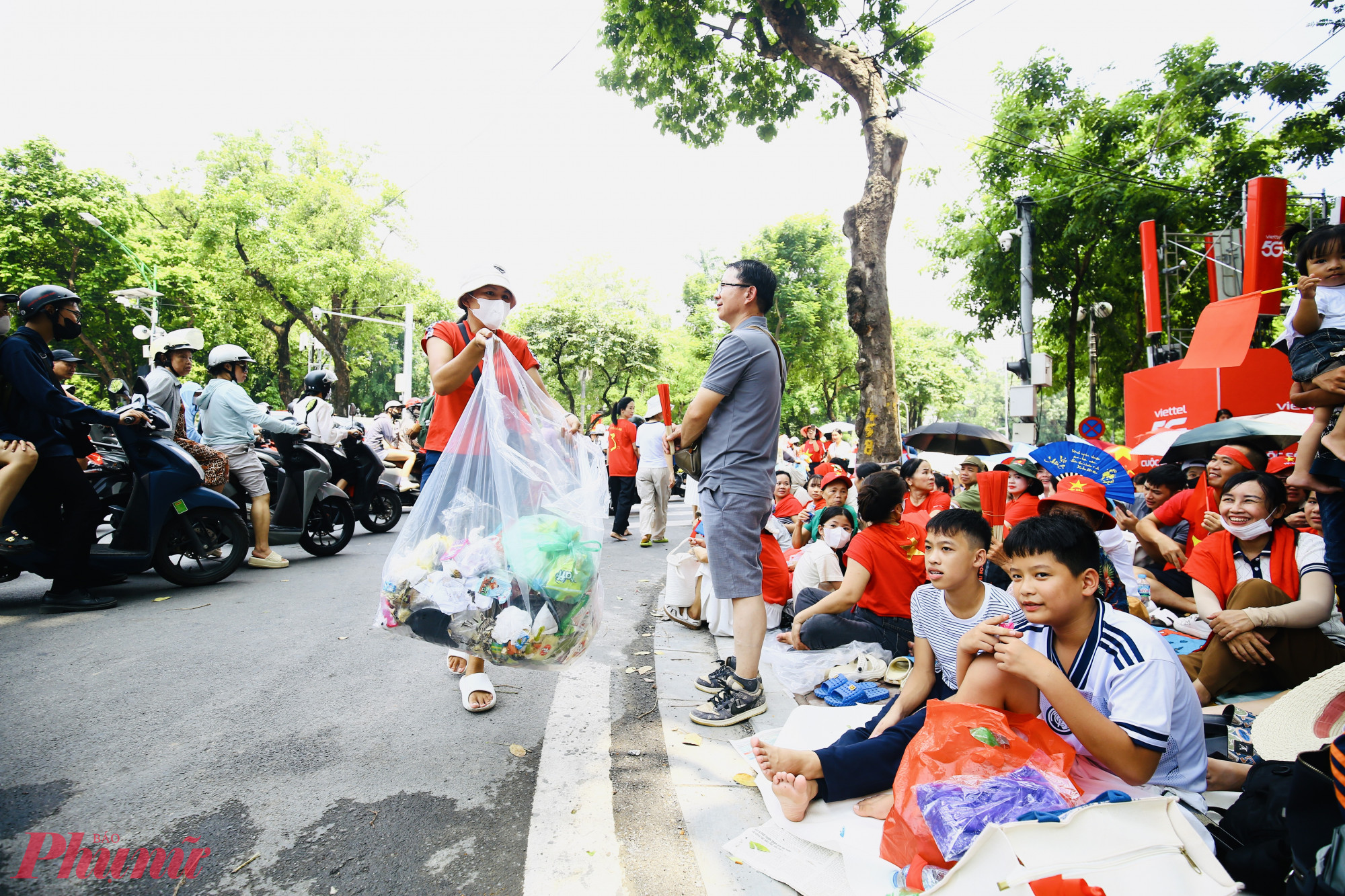 Cô giáo dạy bơi hóa công nhân môi trường, dọn rác cho người dân xem diễu binh, diễu hành Trưa 24/8, trên tuyến đường Trần Phú – Nguyễn Thái Học, một người phụ nữ cầm túi bóng lớn trên tay, đi dọc theo vỉa hè để gom rác cho người dân ngồi xếp hàng chờ xem diễu binh, diễu hành. Chị cho biết, mình là giáo viên dạy bơi ở khu vực phường Quán Thánh, hôm nay “bổ sung” là công nhân môi trường, một ngày đi 5 lượt để góp phần giữ gìn không gian xanh – sạch – đẹp trong ngày lễ lớn của đất nước.
