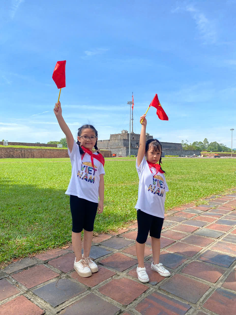 Hai chị em chụp ảnh với lá cờ Tổ quốc bên cột cờ Phu Văn Lâu (Ảnh: Bích Thuận)