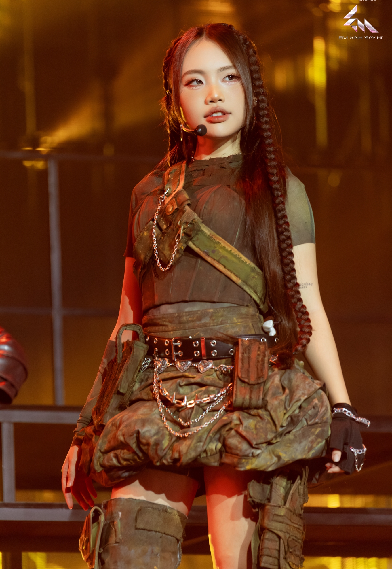 Trong tạo hình như một nữ chiến binh tương lai, Phương Mỹ chi diện outfit phá cách, nhấn nhá bằng corset ôm sát, dây xích và thắt lưng đinh tán cá tính. Kiểu tóc tết dài hai bên kết hợp makeup sắc sảo giúp giọng ca trẻ toát lên thần thái mạnh mẽ, gai góc nhưng vẫn quyến rũ.