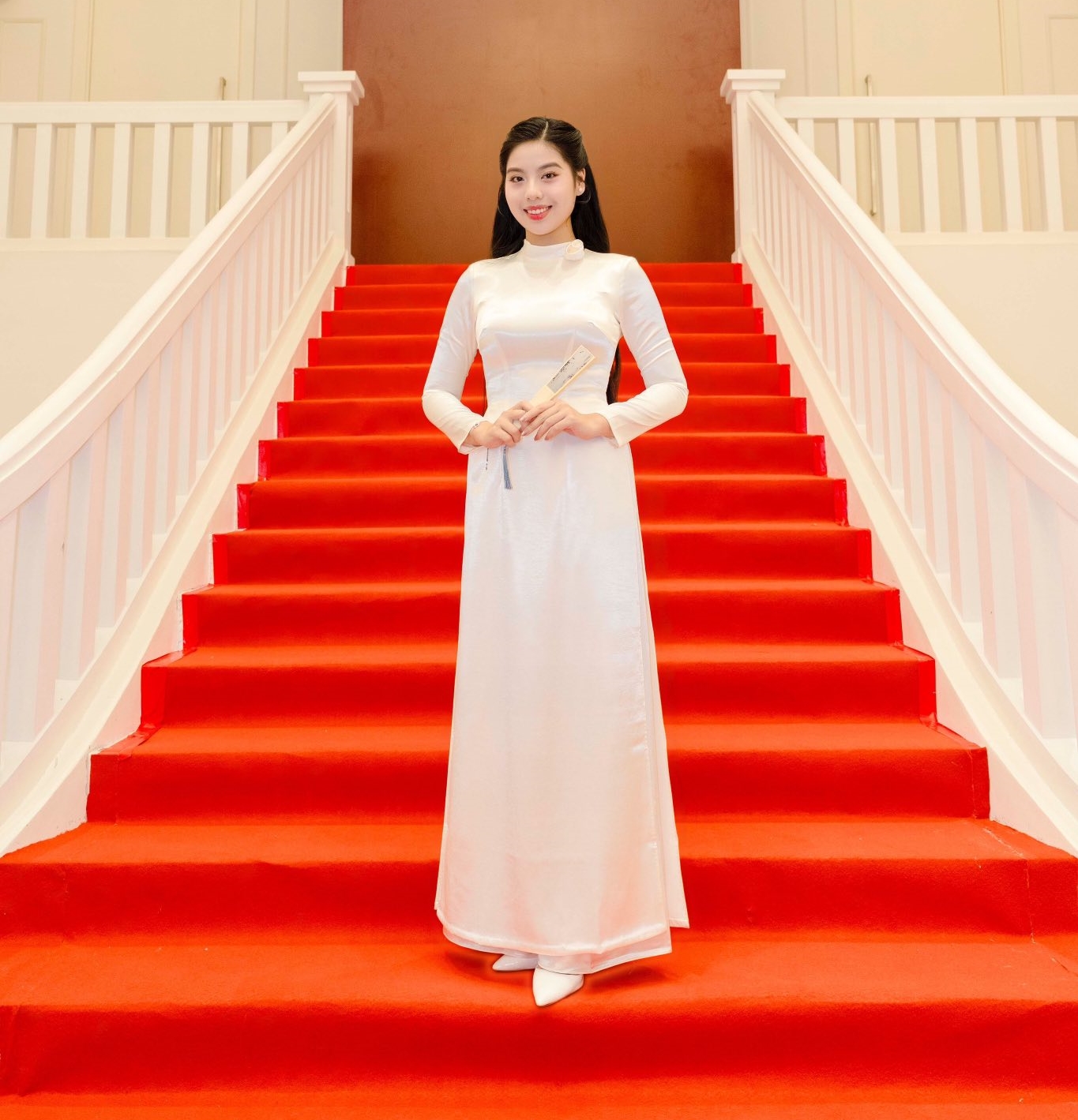 Ngô Ngọc Gia Hân toát lên vẻ đẹp thuần khiết và thanh lịch trong tà áo dài trắng truyền thống. Gương mặt cô rạng rỡ với làn da trắng sáng, nụ cười nhẹ nhàng cùng phong thái tự tin, duyên dáng. Mái tóc dài suôn mượt được chải gọn gàng, càng tôn lên nét đẹp dịu dàng, đậm chất Á Đông