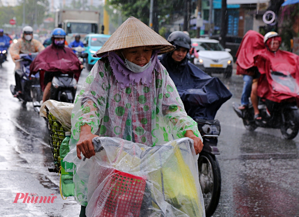 Đến 9h30 sáng cùng ngày, mưa vẫn còn xảy ra tại nhiều khu vực. Trong ảnh người phụ nữ chật vật trong mưa gió chở xe trái cây vào khu trung tâm TP mưu sinh.