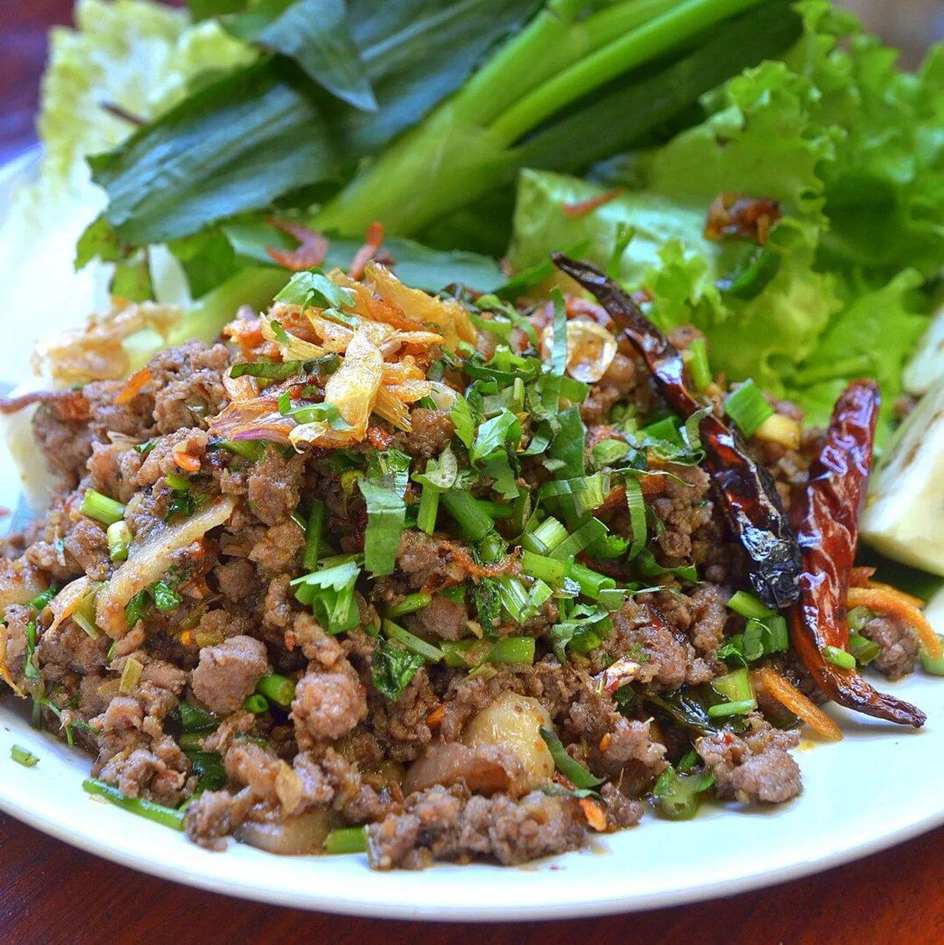 Lap Khmer còn được gọi là gỏi bò tái chanh Khmer. Thịt bò cắt mỏng, trộn với nước cốt chanh tươi để làm tái. Sau đó trộn hỗn hợp sốt: tỏi băm, hành khô, ớt, nước mắm, đường thốt nốt, nước cốt chanh và cho vào thêm rau thơm. Gỏi ăn cùng với cơm nóng hoặc làm món khai vị - Ảnh: Takeaway