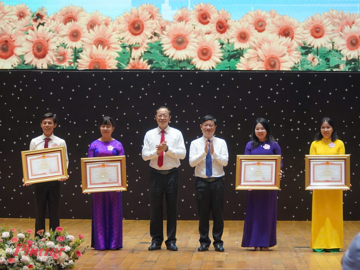 Thứ trưởng Phạm Ngọc Thưởng và ông Võ Văn Minh - Phó bí thư Thành ủy, Chủ tịch HĐND TPHCM trao bằng khen của Chính phủ cho các đơn vị có thành tích xuất sắc trong năm học vừa qua - Ảnh: Trang Thư