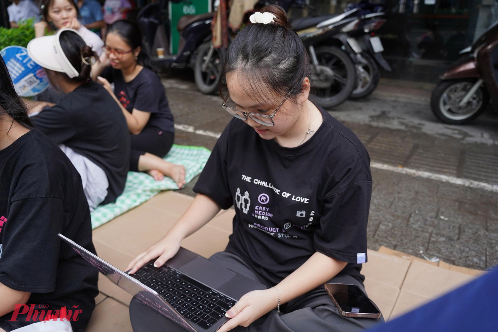 Một bạn trẻ đang học online ngay trên vỉa hè, chờ đoàn diễu binh, điêu hành.