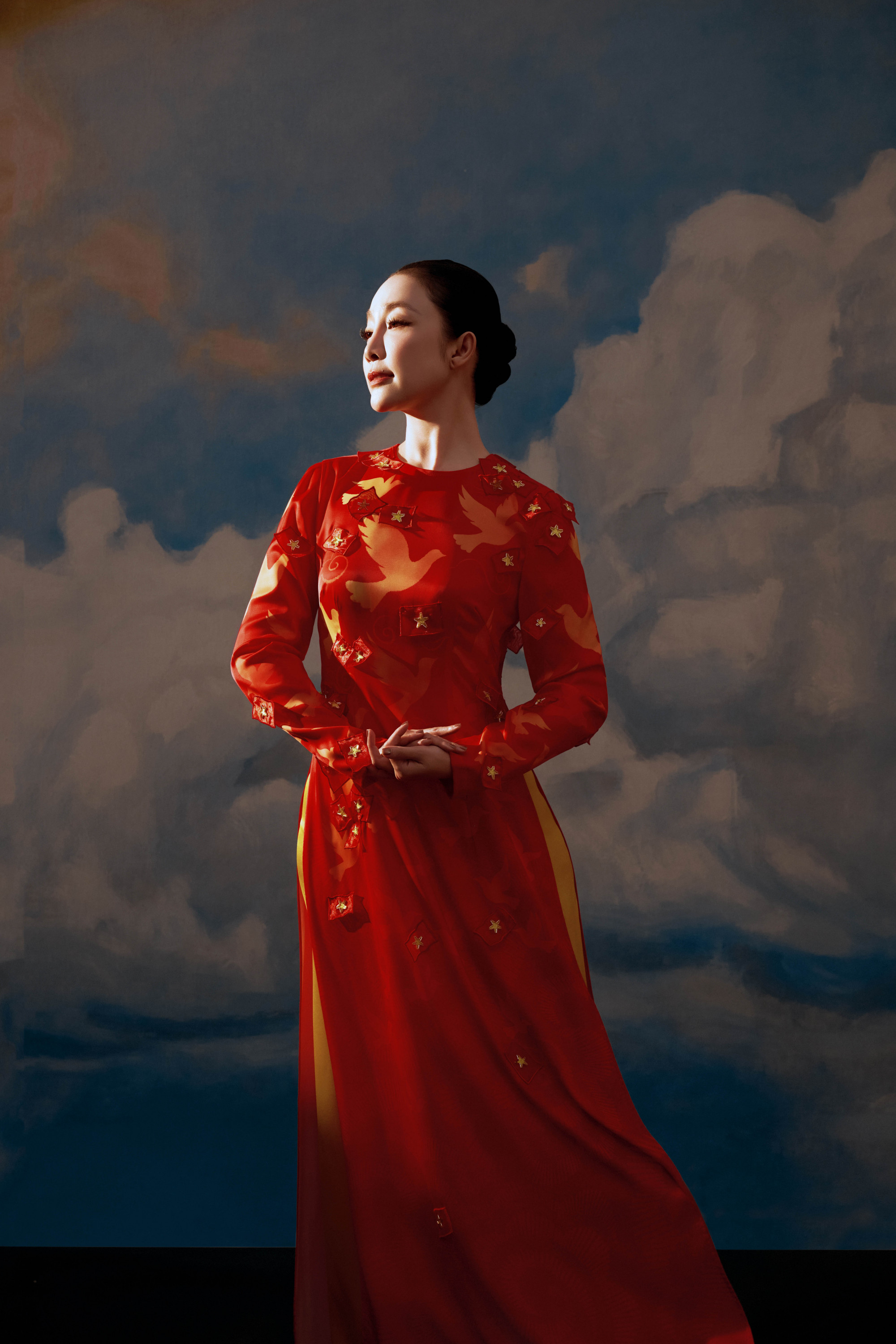 Diện thiết kế áo dài được điểm xuyết những họa tiết chim bồ câu và ngôi sao vàng, gợi nhắc đến hình ảnh hòa bình và tinh thần đoàn kết, Linh Nga toát lên vẻ đẹp thanh tú, quý phái. Kiểu tóc búi gọn càng tôn lên đường nét thanh lịch và phong thái trang nhã của cô.