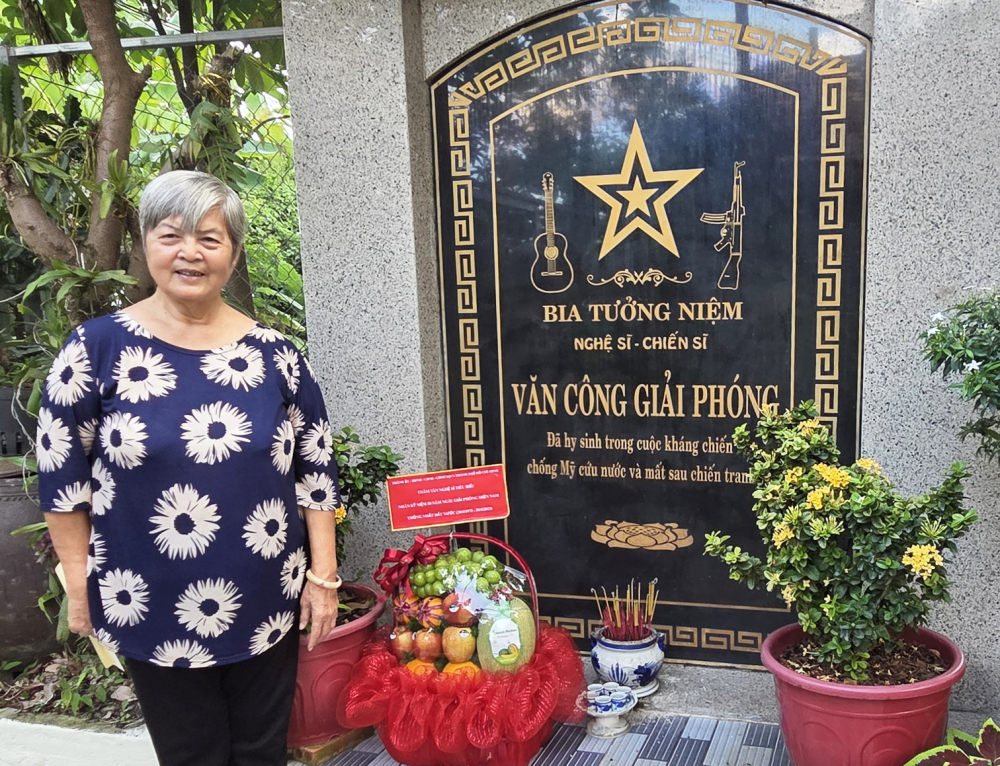 Nghệ sĩ ưu tú Phi Yến bên bia tưởng niệm đồng đội, đồng chí đã hy sinh được bà xây dựng tại nhà mình - ẢNH: NGỌC TUYẾT
