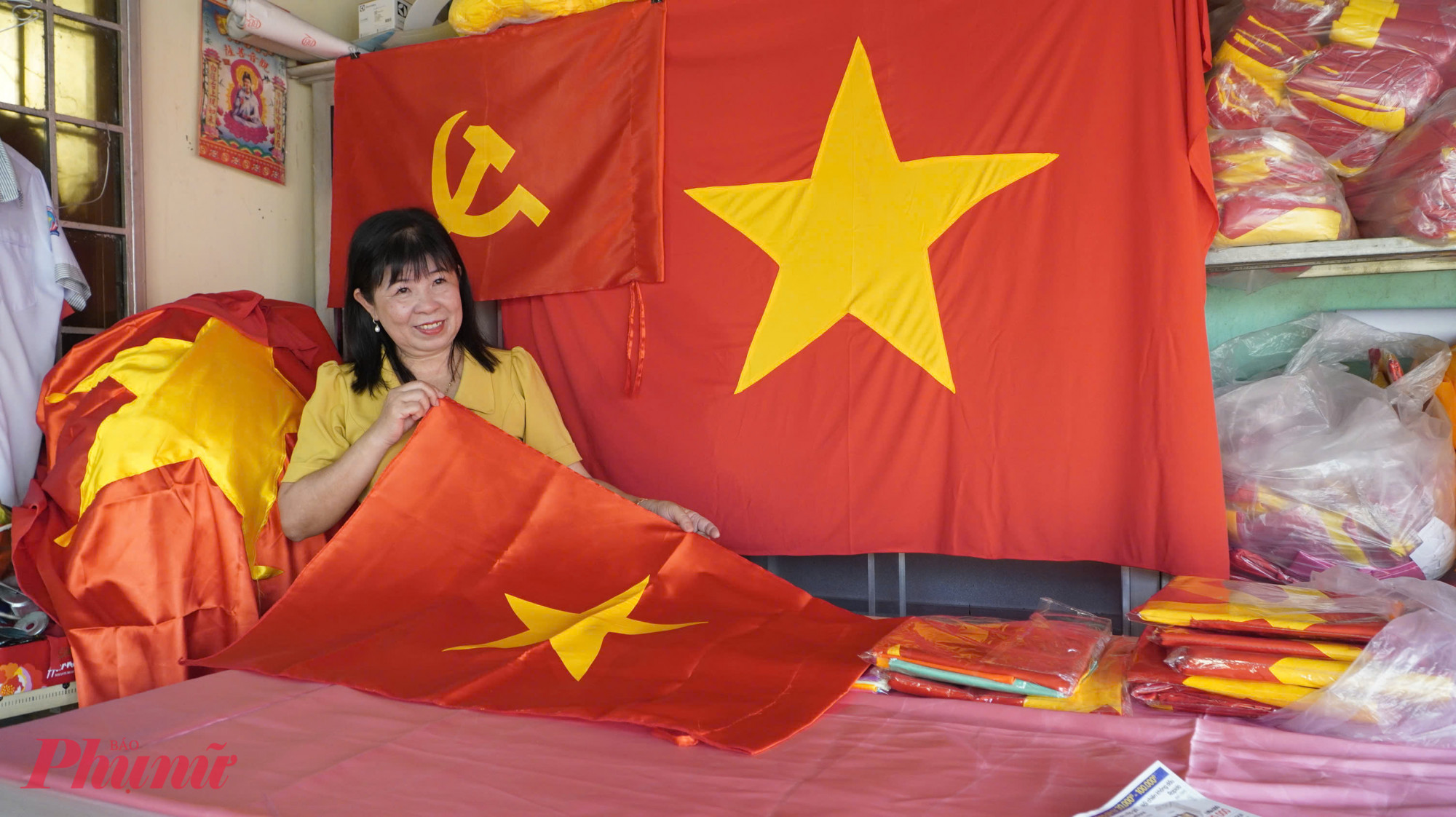 Chị Nguyễn Kiều Thu cùng sản phẩm lá cờ được may tại cơ sở của chị - Ảnh Phú Hữu