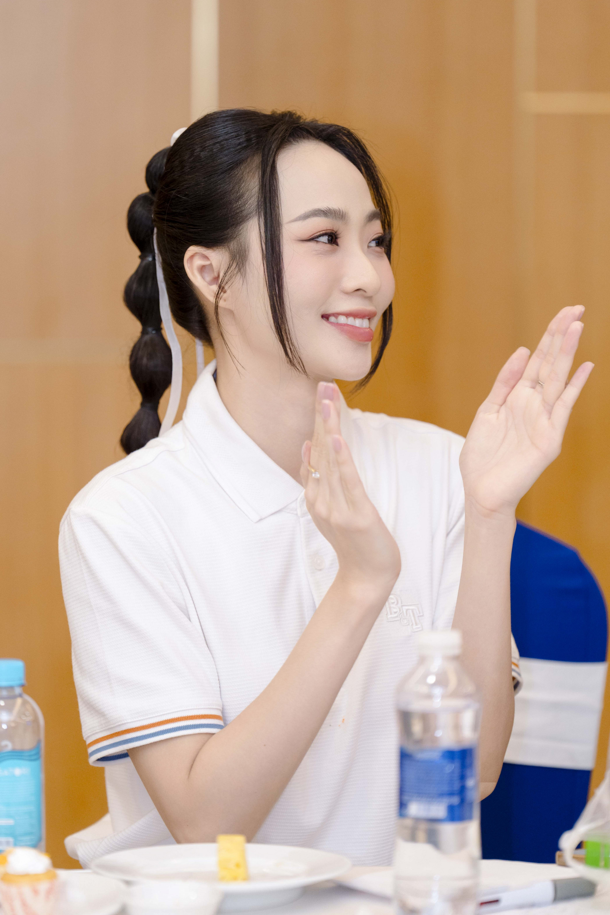 Trong mỗi khung hình, Trà My toát lên vẻ đẹp nhẹ nhàng và rạng rỡ với làn da trắng mịn, nụ cười tươi và ánh mắt đầy sức sống. Cô diện áo polo trắng đơn giản, kết hợp kiểu tóc tết đuôi bong bóng cột cao cùng ruy băng trắng, tạo nên phong cách trẻ trung, nữ tính. Lối trang điểm nhẹ nhàng với tông hồng tự nhiên, kẻ mắt mảnh và má ửng hồng càng làm nổi bật vẻ đẹp trong sáng, thanh lịch của cô.