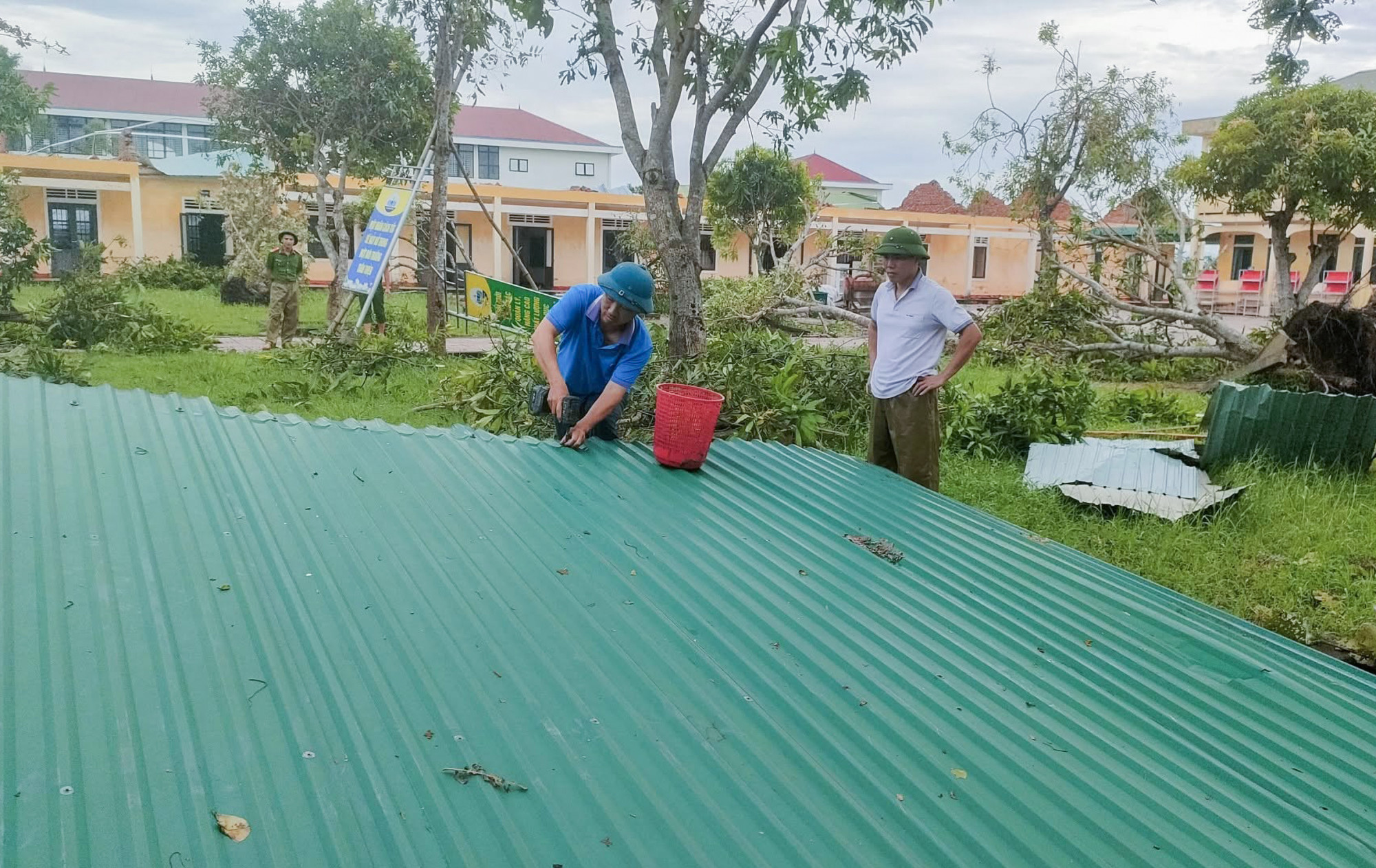 Những tấm tôn bị gió bão thổi bay nhưng chưa bị vò nát được tận dụng để lợp lại mái nhà - Ảnh: Khánh Trung