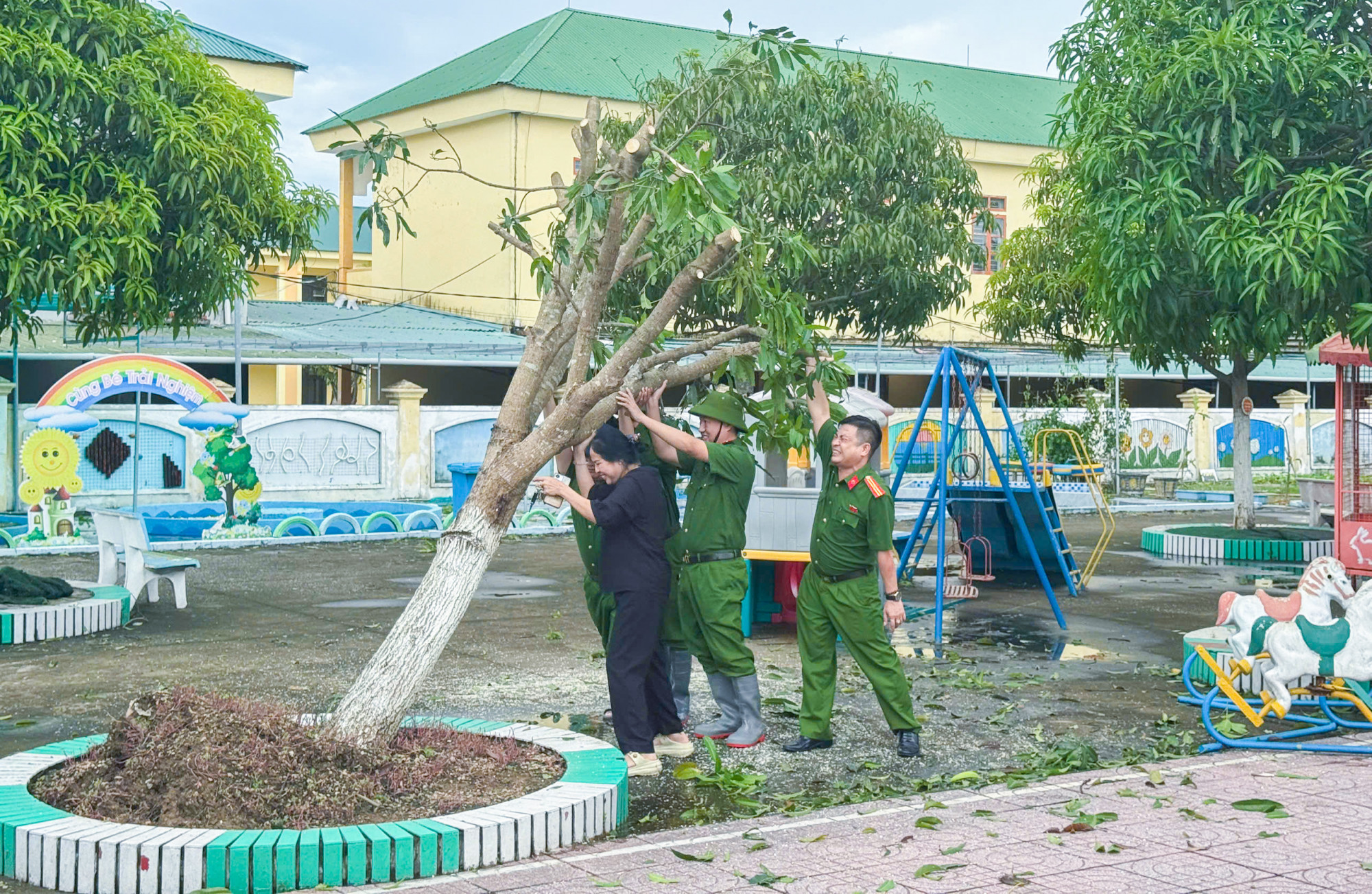 Công an hỗ trợ các giáo viên dọn vệ sinh trường lợp, trồng lại cây xanh bị gãy đổ để chuẩn bị cho năm học mới