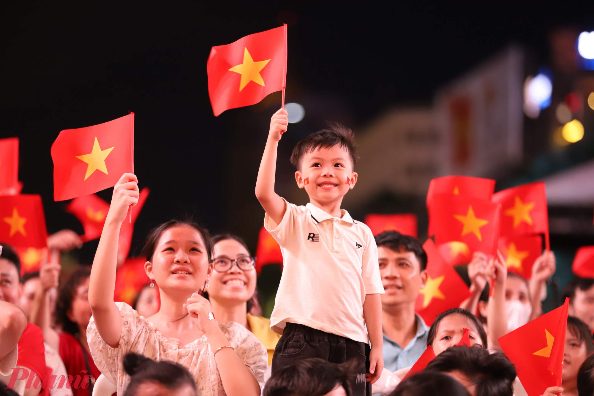 Một em bé cầm cờ đỏ sao vàng hưởng ứng không khí ngày Quốc khánh cùng gia đình
