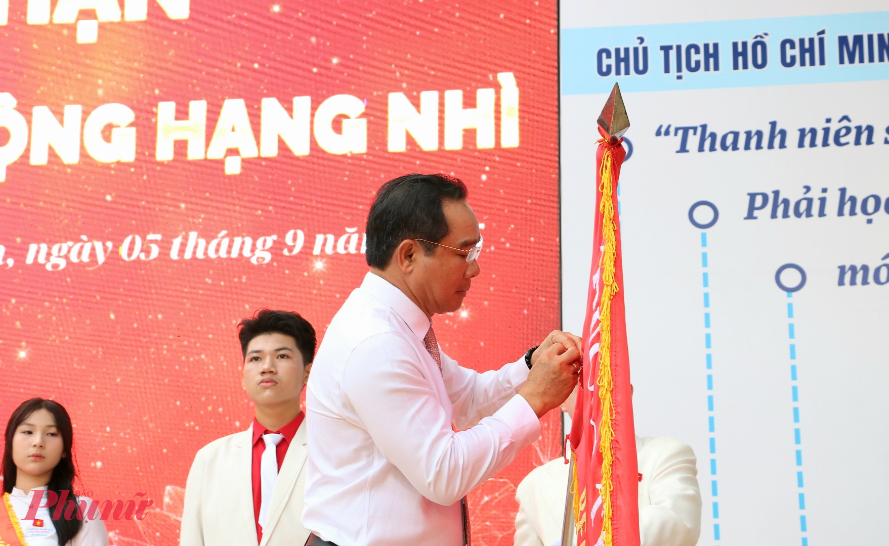 Ông Nguyễn Văn Được - Phó Bí thư Thành ủy, Chủ tịch UBND thành phố - cài Huân chương Lao động hạn Nhì lên cờ truyền thống của nhà trường - Ảnh: Trang Thư