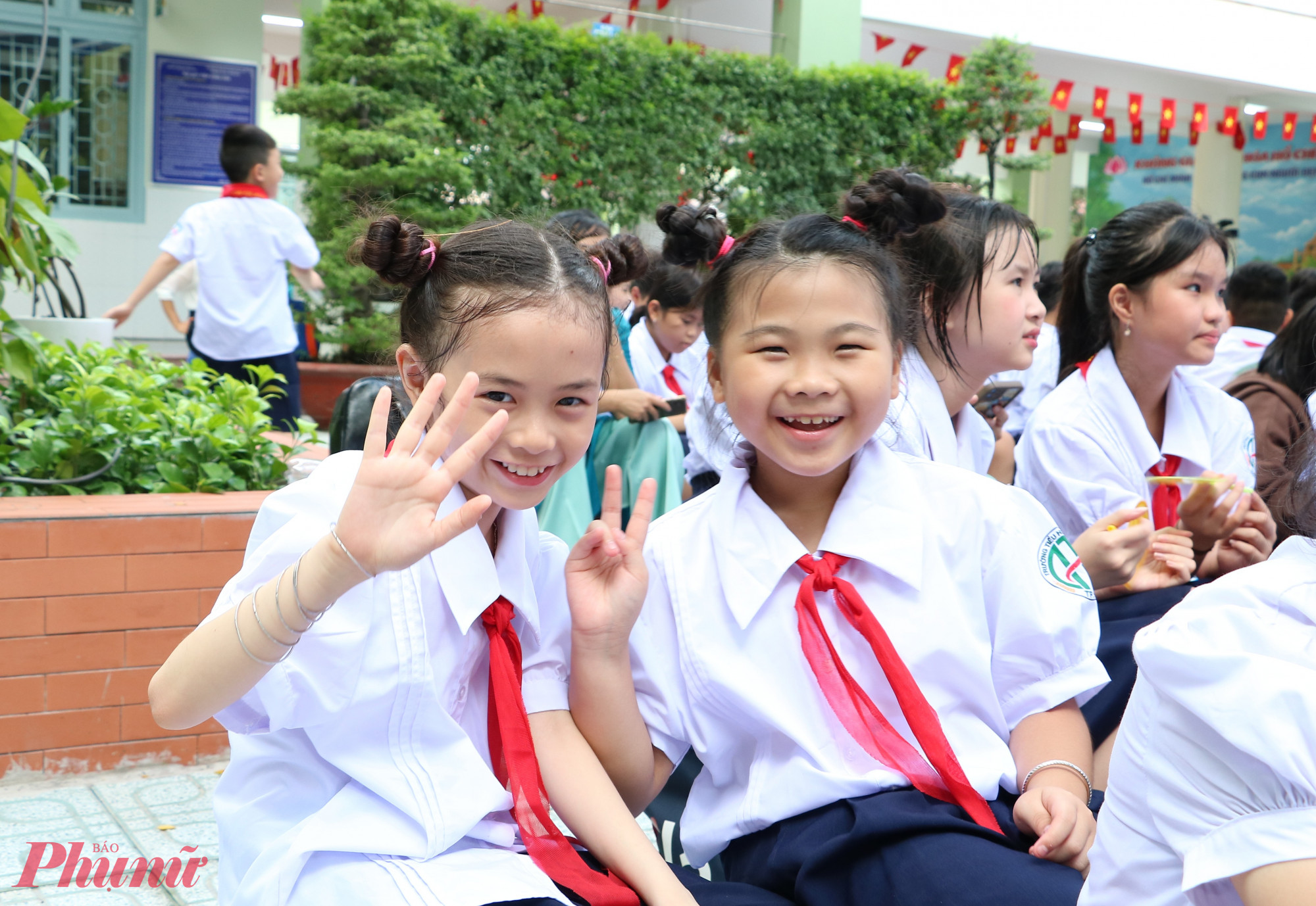 Đôi bạn Khả Ân - Uyên Nhi (từ trái qua) - học sinh lớp Bốn 5 - chỉnh trang lại khăn quàng trước giờ làm lễ 