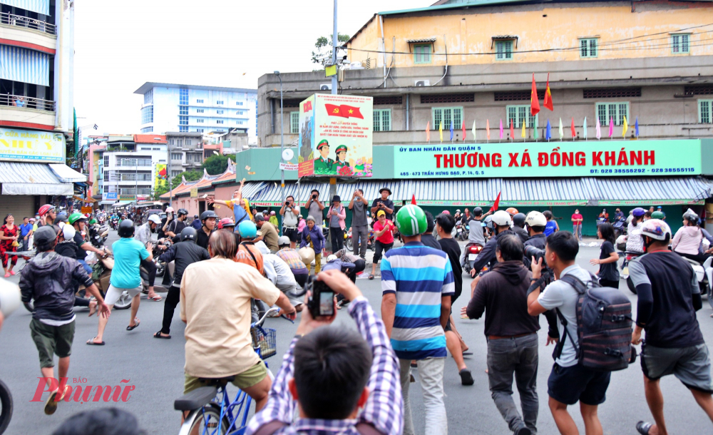 Khoảng 17h cùng ngày, trong lúc chờ đợi gia đình ông Trần Văn Trí (63 tuổi, phường Chợ Lớn) cúng cô hồn rồi rải tiền theo phong tùng, một người dân đi xe máy ngang qua vong xoay bất ngờ vung tiền lên cao bay khắp nơi. Lúc này cả trăm thanh niên nhanh chóng lao vào giành giật khiến tuyến đường trở nên náo loạn, nhiều phương tiện phải dừng gấp. 
