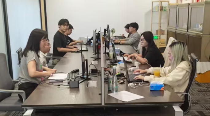 Người dùng trẻ tuổi làm việc tại bàn làm việc chung bên trong Công ty giả vờ làm việc không giới hạn Hàng Châu, một không gian văn phòng giả cung cấp thói quen và cấu trúc trong trường hợp không có việc làm chính thức. (Ảnh: Công ty giả vờ làm việc không giới hạn Hàng Châu)
