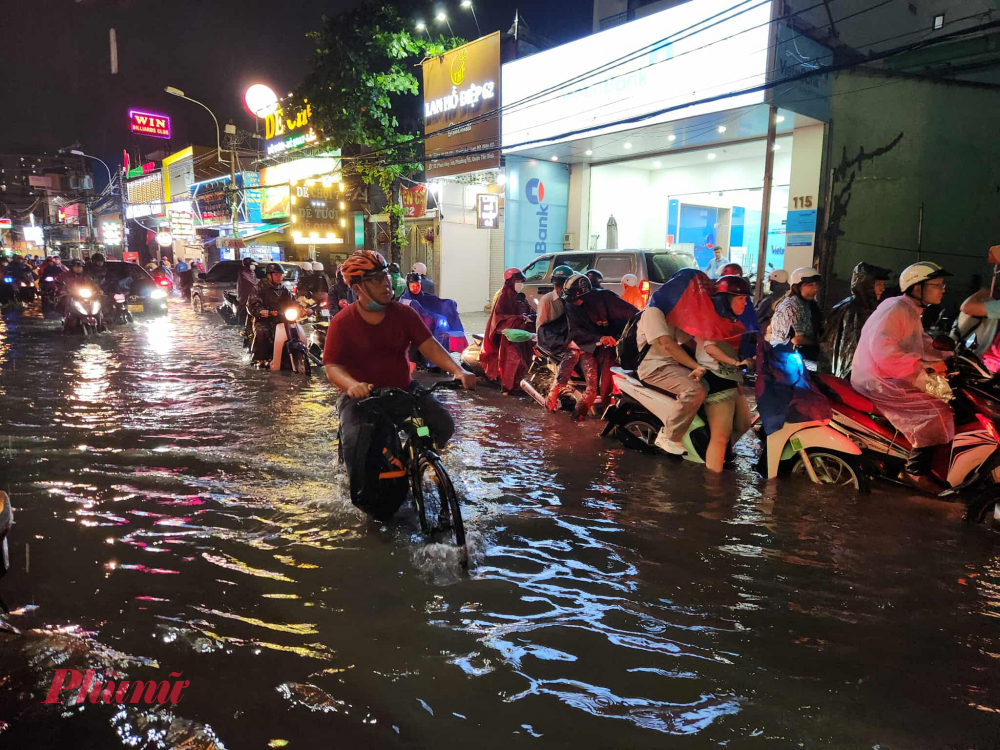 Người đi xe đạp chật vật vượt đường ngập như sông. Ảnh Nguyễn Văn
