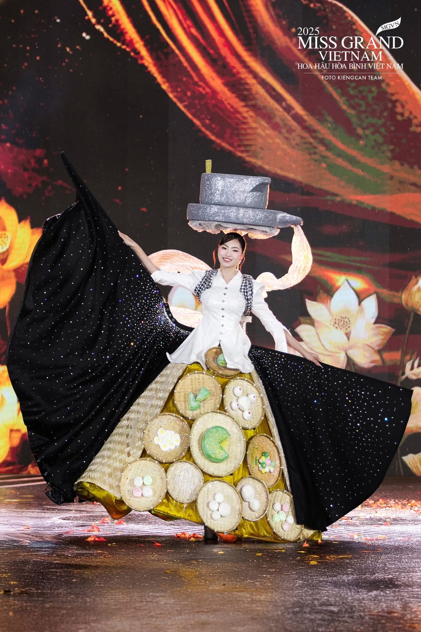 Bộ cánh Tinh khôi nghề bột của tác giả Nguyễn Phước Thịnh mang thông điệp ý nghĩa khi tôn vinh nét đẹp ẩm thực truyền thống Việt Nam, đặc biệt là nghề làm bánh bột - một di sản gắn bó với đời sống dân dã của người dân Nam Bộ. Các chi tiết như mẹt tre, bánh bột nhiều màu sắc được đưa vào trang phục tạo cảm giác sinh động và gần gũi. Tuy nhiên, thiết kế lại nặng nề và nhiều chi tiết rườm rà, khiến tổng thể trở nên cồng kềnh. Phần chân váy rộng kết hợp các mâm bánh khiến người mặc khó di chuyển linh hoạt, trong khi phần mũ đội đầu quá lớn gây mất cân đối.