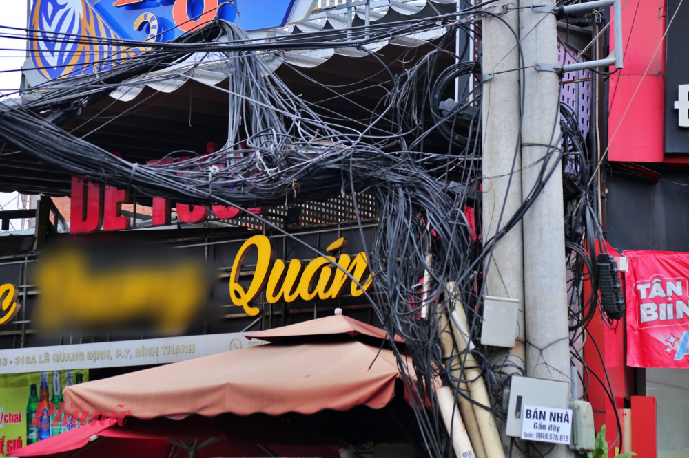 Bảng hiệu của một quán nhậu sát với trụ điện chằng chịt dây điện. 