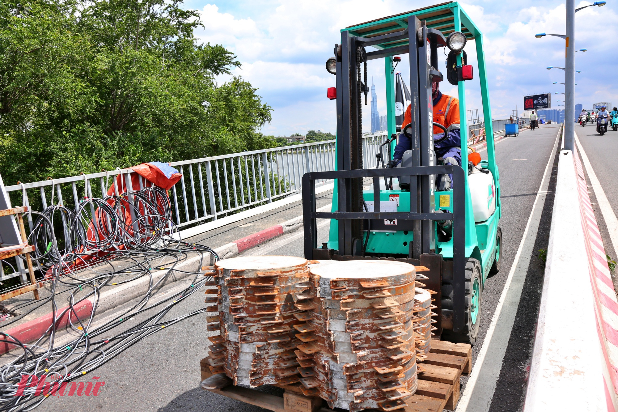 Hình ảnh xe nâng đang vận chuyển các gối cầu mới bằng bê tông cốt thép đến các vị trí trên cầu. Thời gian qua, thời tiết TPHCM sáng nắng, chiều mưa cũng đã ảnh hưởng không nhỏ đến việc nâng tĩnh không cầu. Mặc dù vậy, đội ngũ công nhân, kỹ sư vẫn làm việc ngày đêm để đảm bảo tiến độ. 
