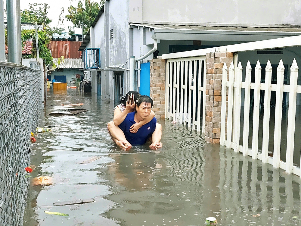 Chồng cõng vợ vượt qua điểm ngập ở khu dân cư trên đường tỉnh lộ 43, phường Tam Bình, TPHCM sau trận mưa hồi tháng 5/2025 ẢNH: TỨ QUÝ
