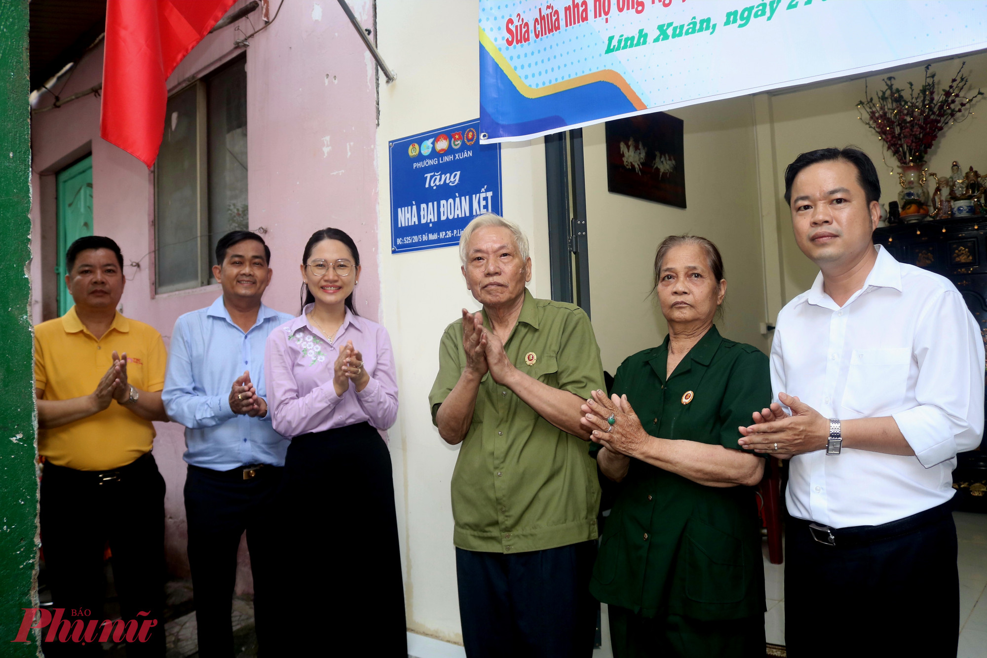 Đại biểu thực hiện nghi thức gỡ bảng tượng trưng tặng nhà đại đoàn kết cho gia đình - Ảnh: Mẫn Nhi