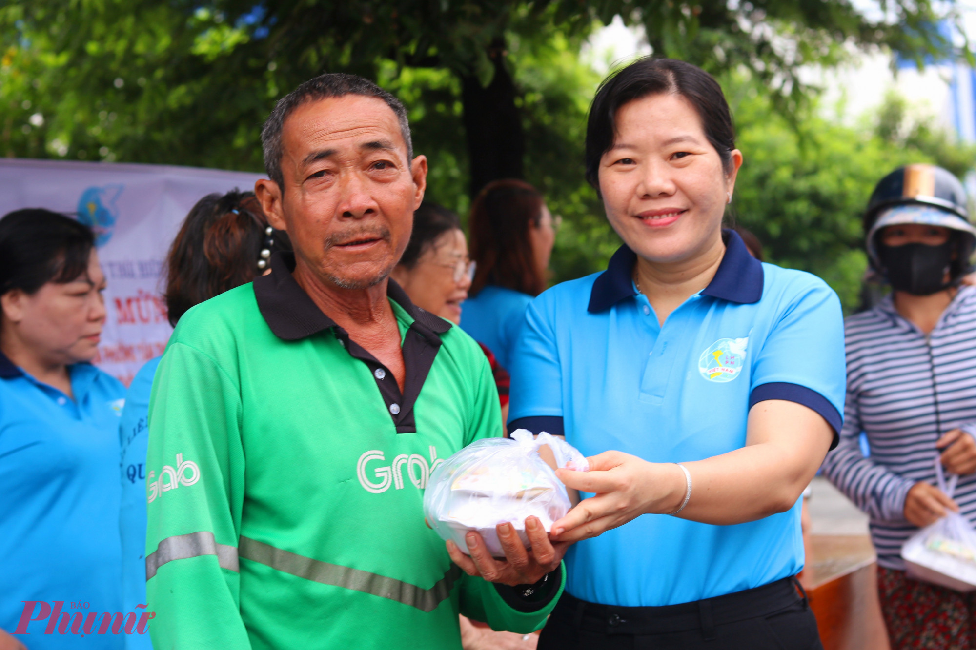 Bà Phạm Thị Mộng Hằng - Phó chủ tịch thường trực Ủy ban MTTQ, Chủ tịch Hội LHPN phường Tân Thới Hiệp – trao hộp xôi cho người lao động đang trên đường đi làm buổi sáng - Ảnh: Thảo Nguyên