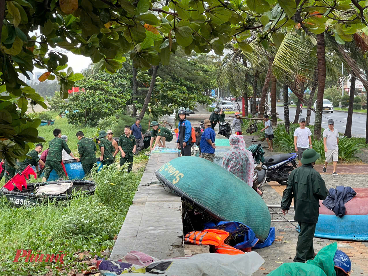 Cán bộ, chiến sĩ Đồn Biên phòng Phú Lộc hỗ trợ ngư dân đưa thuyền thúng lên bờ để tránh trú bão.