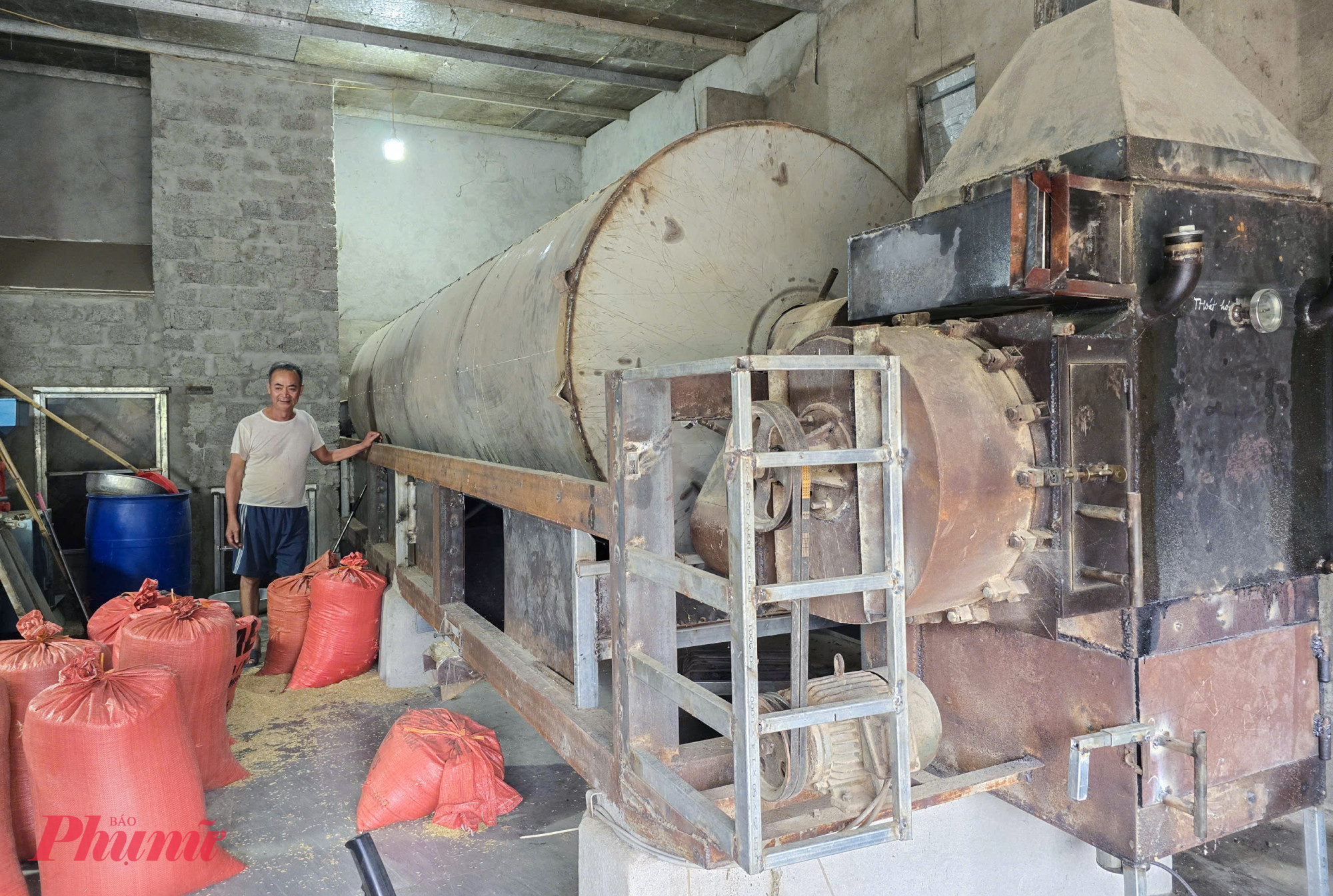 Ông Nam bên chiếc máy sấy lúa do mình chế tạo - Ảnh: Phan Ngọc