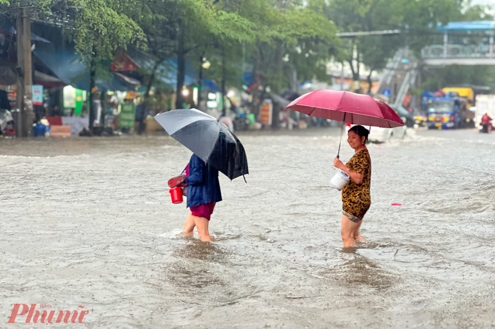 Những người chăm bệnh nhân lội qua đoạn nước ngập sâu nhất để sang đường, chờ vào bệnh viện đưa cơm cho bệnh nhân.