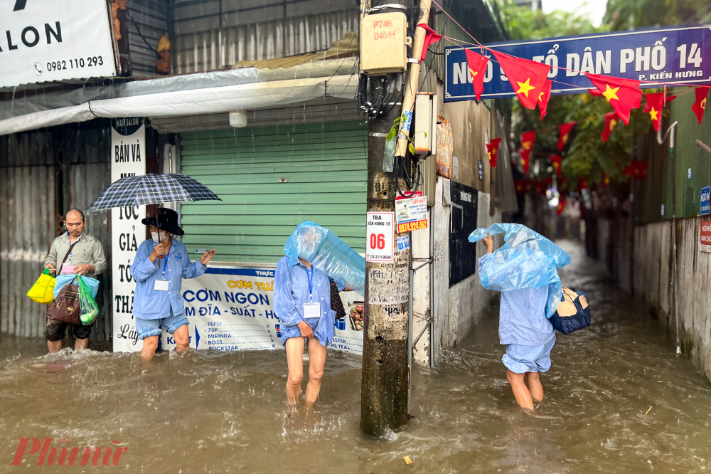 Các bệnh nhân điều trị ngoại trú trọ tại các khu nhà gần bệnh viện K đang lội nước trở về khu trọ.