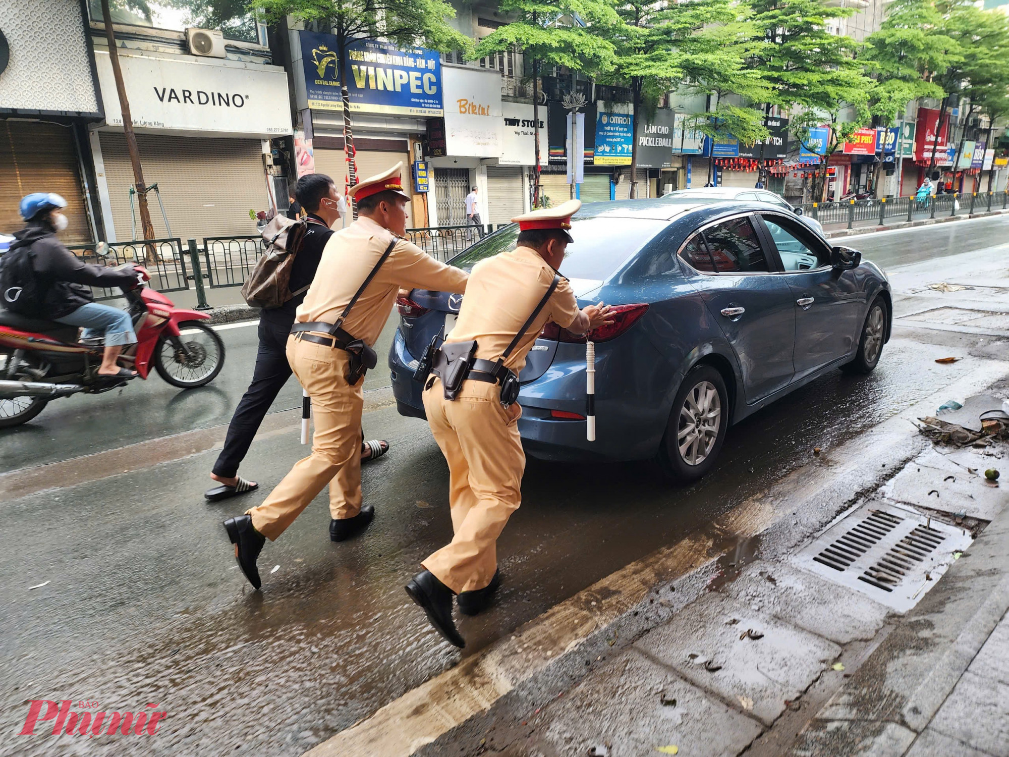 Một chiếc ô tô chết máy giữa dòng nước được cảnh sát hỗ trợ đưa đến điểm an toàn, chờ sửa chữa.