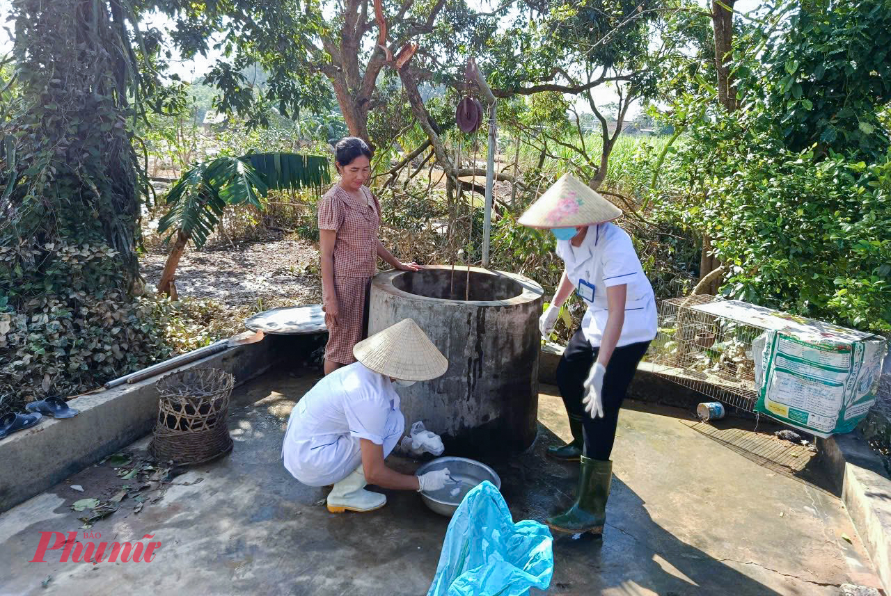 Cán bộ Trạm Y tế xã Nghĩa Hành đến từng nhà hỗ trợ người dân khử khuẩn giếng nước sau lũ - Ảnh: Hoàng Anh