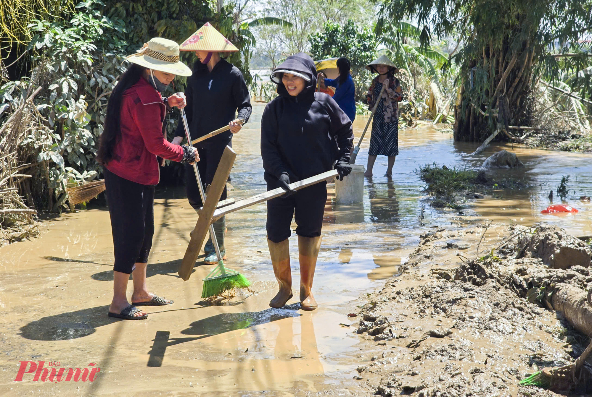 Người dân xã Đô Lương, tỉnh Nghệ An quét dọn, đẩy bùn đất trên đường làng khi nước lũ rút - Ảnh: Phan Ngọc