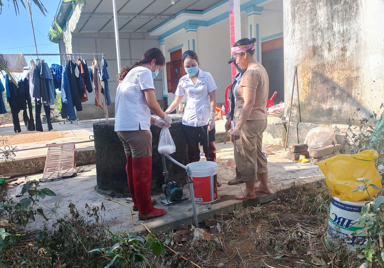 Trạm Y tế xã Nghĩa Hành mang hóa chất đến nhà xử lý giếng nước cho người dân - Ảnh: Khánh Trung