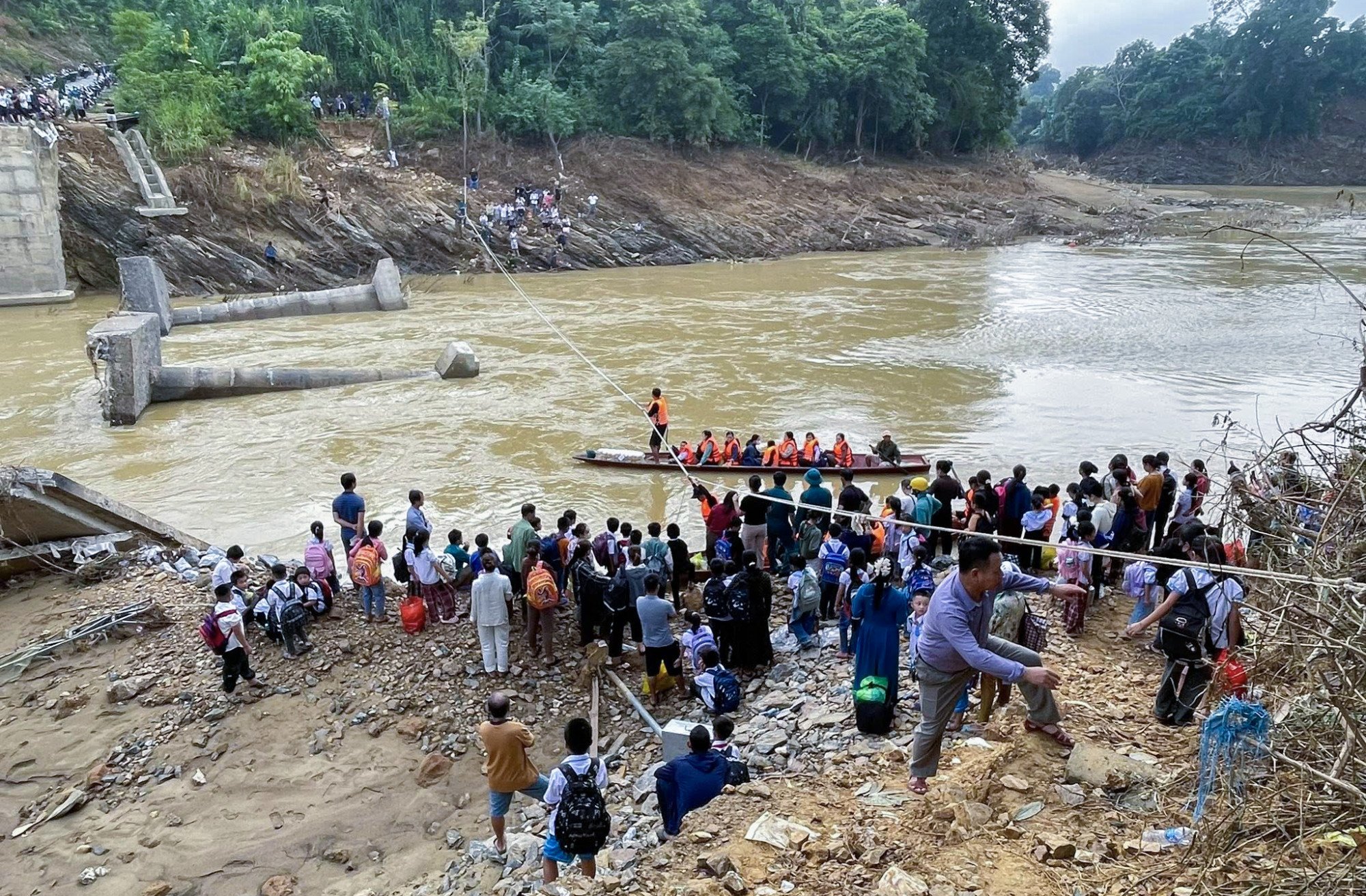 Lực lượng chức năng xã Yên Hòa dùng thuyền, bám vào dây thừng đưa học sinh, giáo viên đến trường