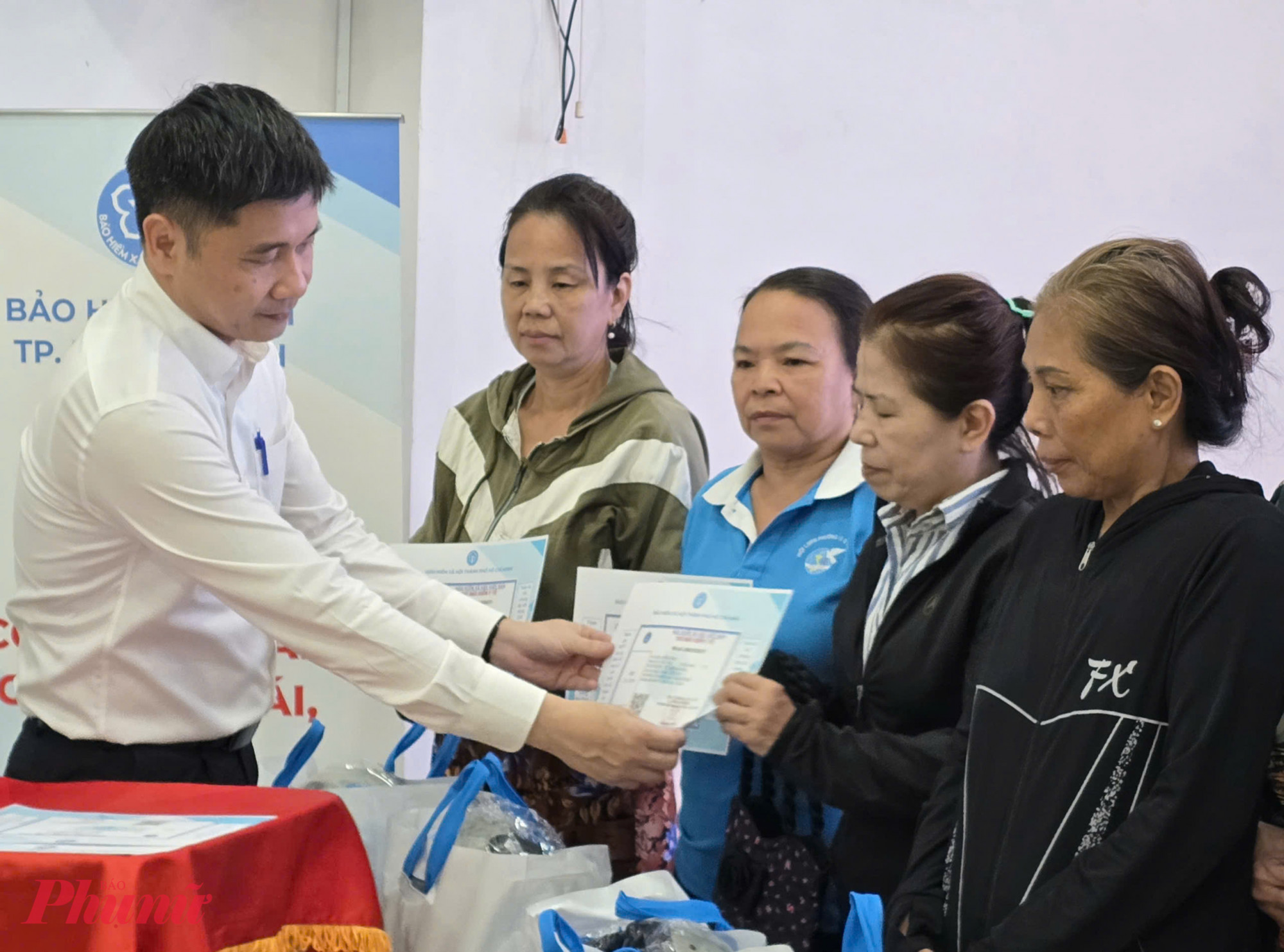 Ông Trần Dũng Hà - Phó Giám đốc BHXH TPHCM trao thẻ BHYT cho hội viên phụ nữ