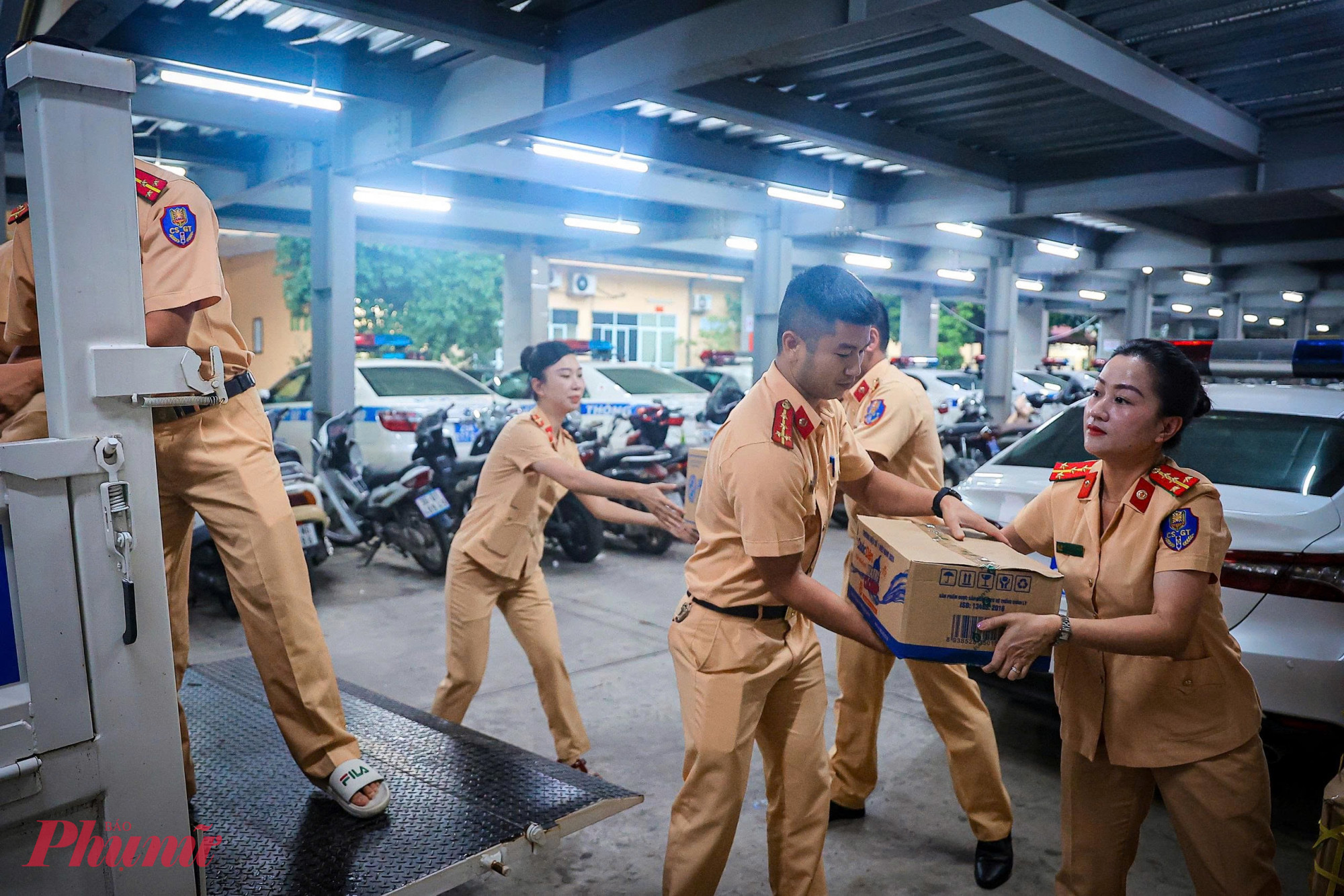 Từng thùng hàng đựng nhu yếu phẩm hỗ trợ người dân được đưa lên xe chuyên dụng, tiến đến vùng lũ.