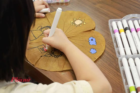 Một em nhỏ đang vẽ tranh trên lá sen tại buổi workshop