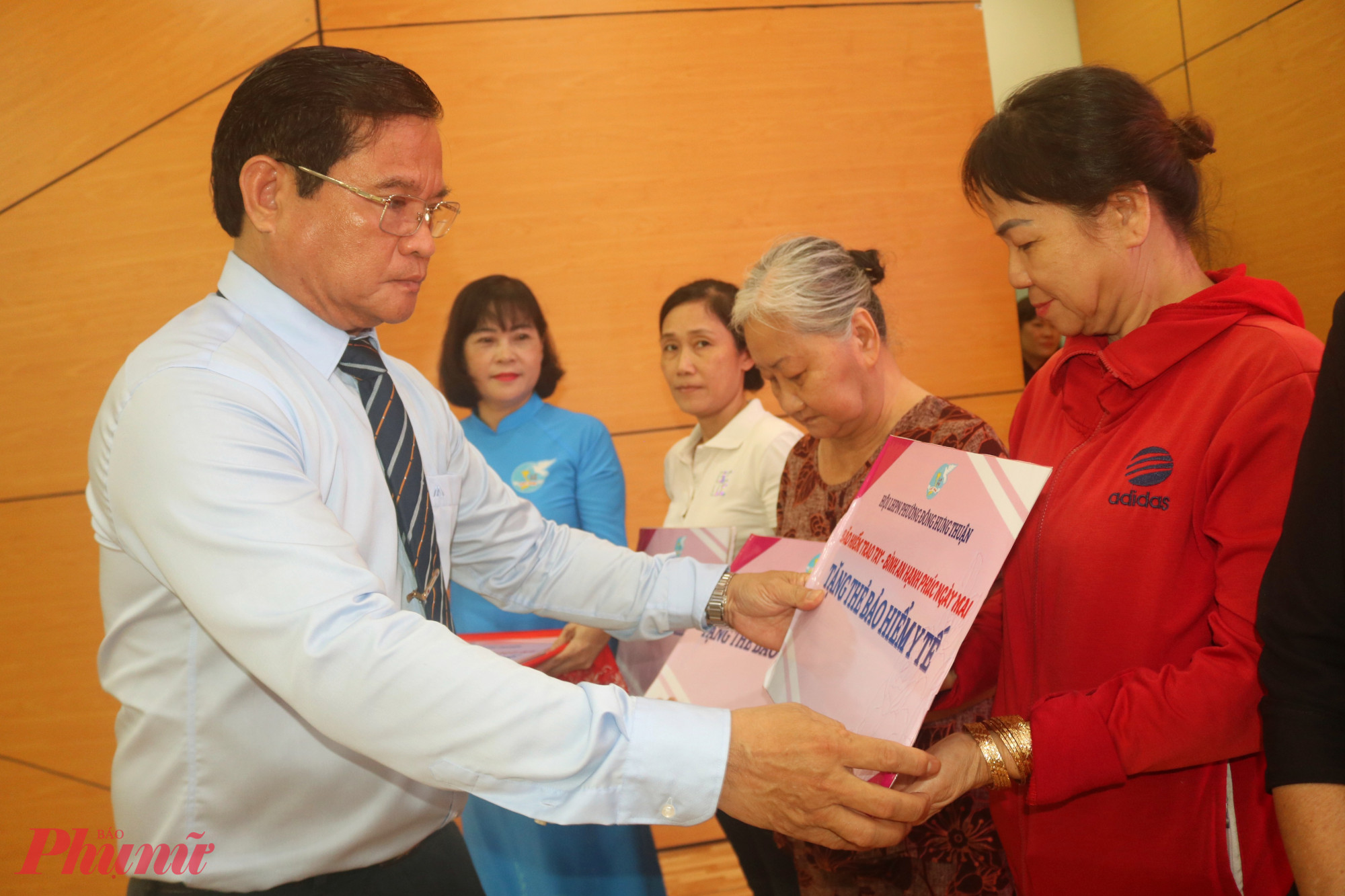 Ông Huỳnh Tấn Việt – Phó bí thư thường trực Đảng ủy phường Đông Hưng Thuận – trao bảng tượng trưng tặng thẻ bảo hiểm y tế đến các dì, các chị - Ảnh: Mẫn Nhi 