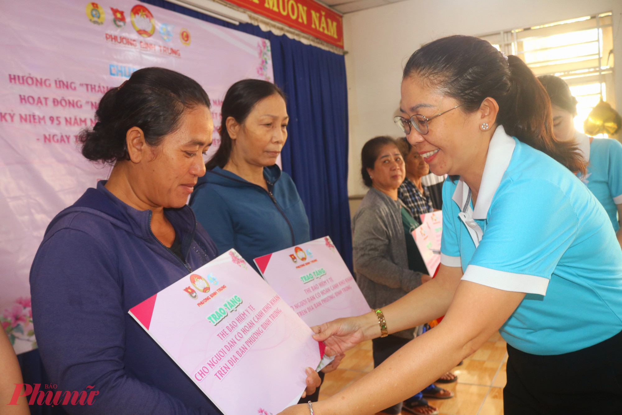 Bà Trần Thị Đoan Trang – Phó chủ tịch Ủy ban MTTQ, Chủ tịch Hội LHPN phường Bình Trưng – trao bảng tượng trưng tặng thẻ bảo hiểm y tế đến các dì, các chị - Ảnh: Mẫn Nhi