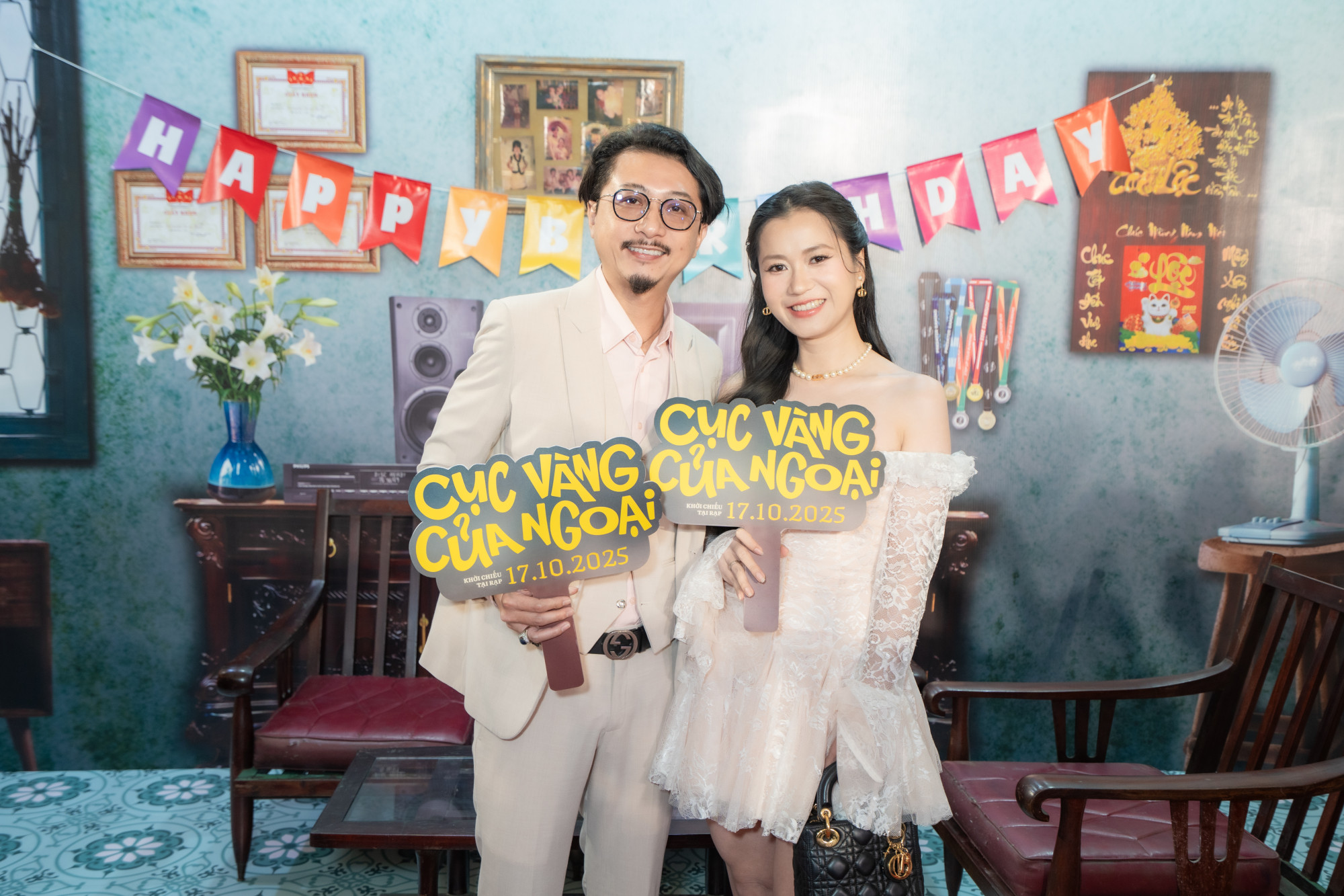 Vợ chồng Hứa Minh Đạt và Lâm Vỹ Dạ rạng rỡ tại sự kiện. Hứa Minh Đạt chọn vest màu kem kết hợp sơ mi hồng phấn nhạt, mang lại cảm giác nhã nhặn, chỉn chu mà vẫn gần gũi. Lâm Vỹ Dạ thu hút ánh nhìn với đầm trễ vai chất liệu ren trắng mềm mại, tôn lên làn da sáng và vẻ đẹp nữ tính, dịu dàng. Cô khéo léo kết hợp phụ kiện ngọc trai và túi xách hàng hiệu, vừa tinh tế vừa sang trọng.