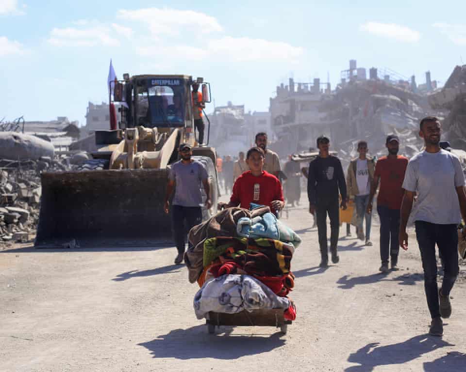 Xe ủi đất chạy qua những người dân di tản trên đường dọn dẹp đống đổ nát trên đường phố ở Thành phố Gaza - Ảnh: Getty Images